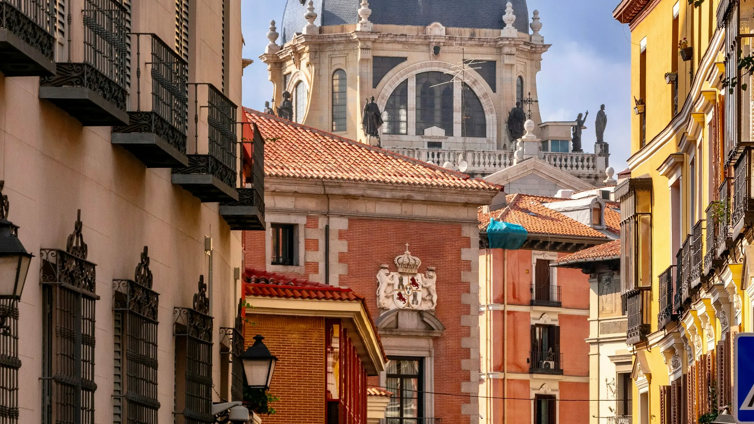 Calle del centro de Madrid con balcones de forja y una cúpula al fondo